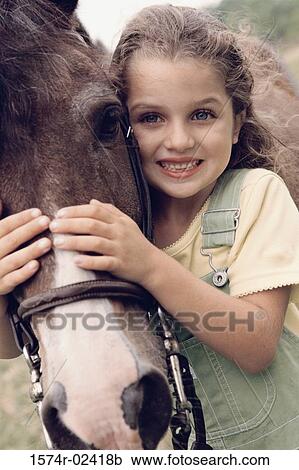 Stock Image - Portrait of a girl standing with a horse. Fotosearch