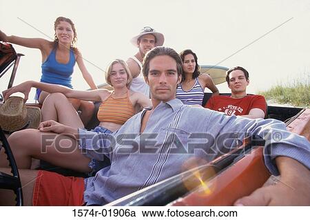 Stock Image - Portrait of a group of young people sitting in a convertible car. Fotosearch