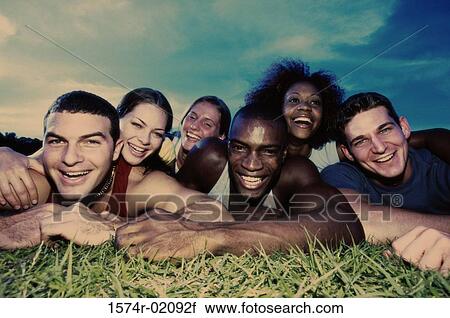 Stock Image - Portrait of a group of young people lying on grass. Fotosearch