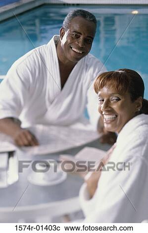 Portrait of a mature couple in bathrobes having breakfast by a swimming pool View Large Photo Image Stock Image - Portrait of a mature couple in bathrobes having breakfast by a swimming pool. Fotosearch