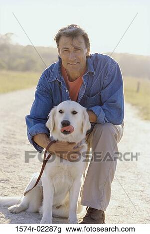 Stock Image - Portrait of a mature man holding his dog. Fotosearch