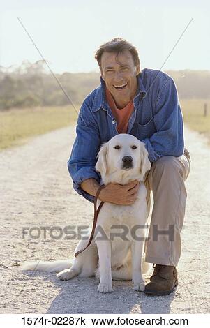 Stock Image - Portrait of a mature man holding his dog. Fotosearch