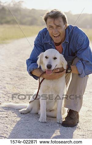 Stock Image - Portrait of a mature man holding his dog. Fotosearch