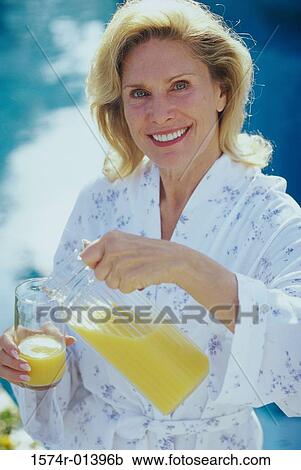 Portrait of a mid adult woman pouring juice from a jug into a glass View Large Photo Image Stock Image - Portrait of a mid adult woman pouring juice from a jug into a glass. Fotosearch