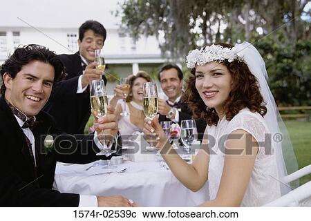 Stock Image - Portrait of a newlywed couple and their friends toasting with champagne glasses. Fotosearch
