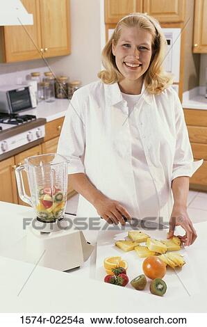 Stock Image - Portrait of a pregnant woman cutting fruit. Fotosearch