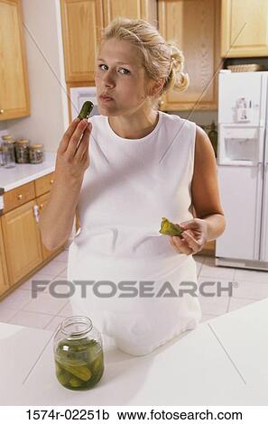 Stock Image - Portrait of a pregnant woman eating pickles. Fotosearch