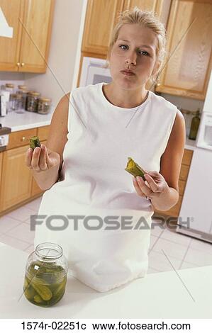 Stock Image - Portrait of a pregnant woman eating pickles. Fotosearch