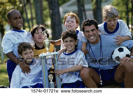 Stock Image - Portrait of a soccer team holding a trophy with their coach. Fotosearch