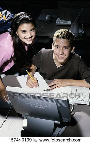 Stock Image - Portrait of a teenage boy and a teenage girl in front of a computer. Fotosearch