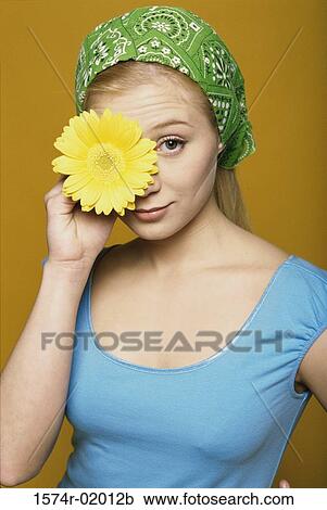 Portrait of a teenage girl holding a flower in front of her eye View Large Photo Image Stock Image - Portrait of a teenage girl holding a flower in front of her eye. Fotosearch