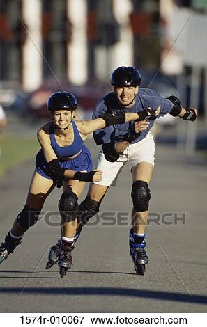 Stock Photo - Portrait of a young couple inline skating on a road. Fotosearch