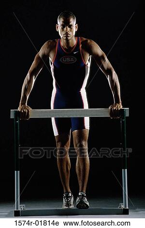 Stock Image - Portrait of a young man resting against a hurdle. Fotosearch