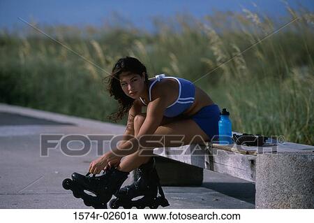 Stock Image - Portrait of a young woman adjusting her inline skates. Fotosearch