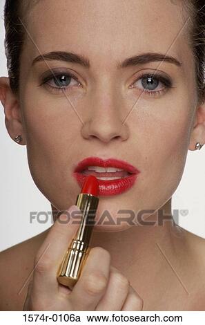 Portrait of a young woman applying lipstick View Large Photo Image Stock Image - Portrait of a young woman applying lipstick. Fotosearch