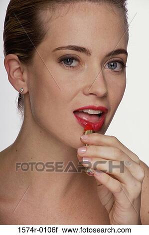 Portrait of a young woman applying lipstick View Large Photo Image Stock Image - Portrait of a young woman applying lipstick. Fotosearch