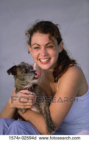 Stock Image - Portrait of a young woman holding her dog. Fotosearch