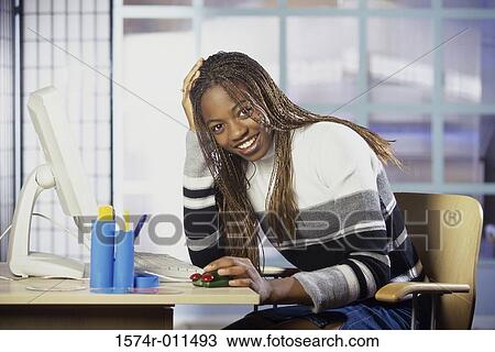 Stock Image - Portrait of a young woman in front of a computer monitor. Fotosearch