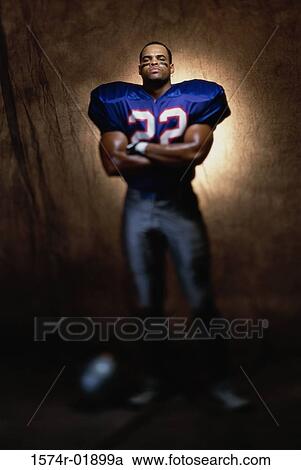 Stock Image - Portrait of an American football player standing with his arms folded. Fotosearch