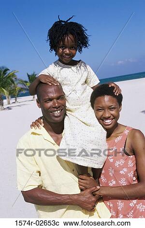 Stock Image - Portrait of parents carrying their daughter on their shoulders. Fotosearch