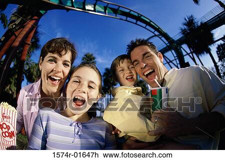 Stock Image - Portrait of parents with their son and daughter in an amusement park. Fotosearch