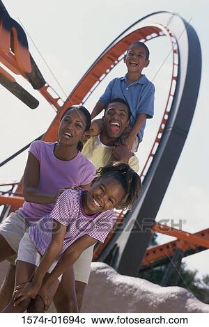 Stock Image - Portrait of parents with their son and daughter at an amusement park. Fotosearch