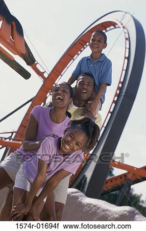 Stock Image - Portrait of parents with their son and daughter at an amusement park. Fotosearch