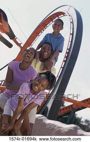 Stock Image - Portrait of parents with their son and daughter at an amusement park. Fotosearch