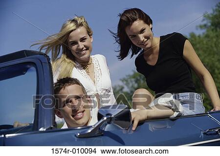 Picture - Portrait of three young people sitting in a convertible car. Fotosearch