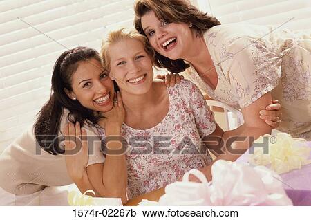Stock Image - Portrait of three young women smiling at a baby shower. Fotosearch