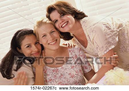 Stock Image - Portrait of three young women smiling at a baby shower. Fotosearch