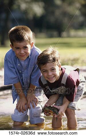 Portrait of two boys standing in water holding a turtle View Large Photo Image Stock Image - Portrait of two boys standing in water holding a turtle. Fotosearch