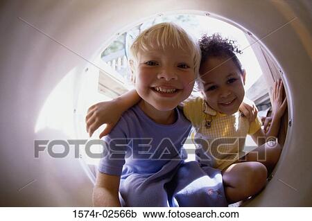 Portrait of two girls crouching together in a tube View Large Photo Image Stock Image - Portrait of two girls crouching together in a tube. Fotosearch