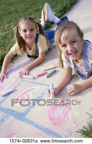 Portrait of two girls drawing on the ground with chalk View Large Photo Image Stock Image - Portrait of two girls drawing on the ground with chalk. Fotosearch
