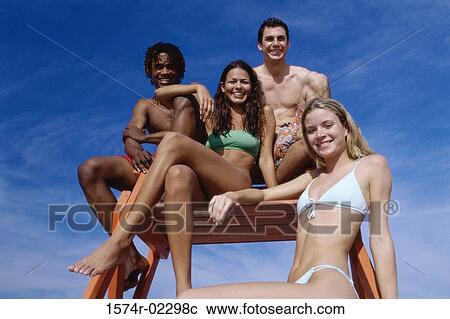 Stock Image - Portrait of two teenage couples sitting on a lifeguard tower. Fotosearch