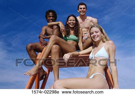 Stock Image - Portrait of two teenage couples sitting on a lifeguard tower. Fotosearch
