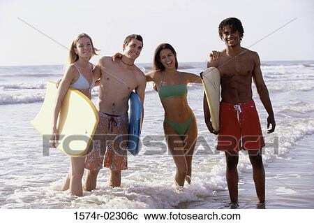 Portrait of two teenage couples standing on the beach holding boogie boards View Large Photo Image Stock Image - Portrait of two teenage couples standing on the beach holding boogie boards. Fotosearch