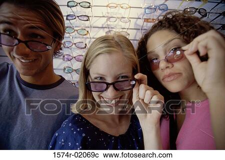 Stock Image - Portrait of two teenage girls and a teenage boy wearing sunglasses. Fotosearch