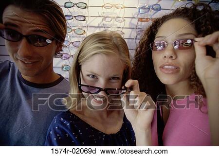 Stock Image - Portrait of two teenage girls and a teenage boy wearing sunglasses. Fotosearch