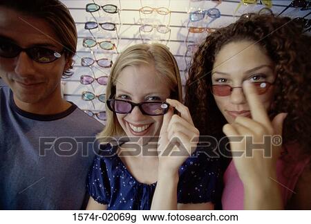 Stock Image - Portrait of two teenage girls and a teenage boy wearing sunglasses. Fotosearch