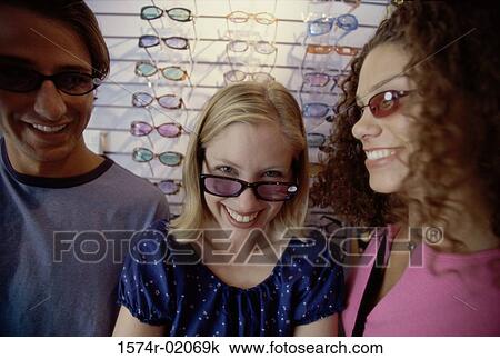 Stock Image - Portrait of two teenage girls and a teenage boy wearing sunglasses. Fotosearch