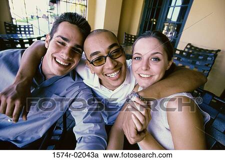 Stock Image - Portrait of two young men and a young woman smiling. Fotosearch