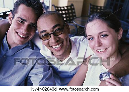 Stock Image - Portrait of two young men and a young woman laughing. Fotosearch