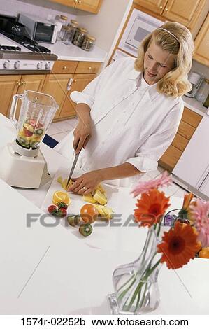 Stock Image - Pregnant woman cutting fruit. Fotosearch