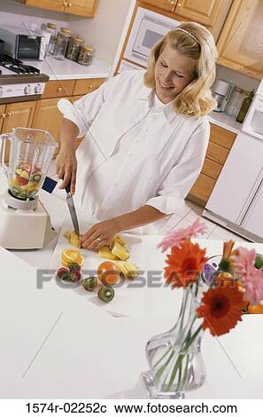Stock Image - Pregnant woman cutting fruit. Fotosearch