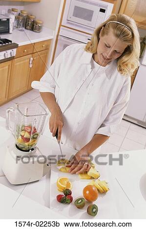 Stock Image - Pregnant woman cutting fruit. Fotosearch