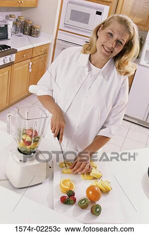 Stock Image - Pregnant woman cutting fruit. Fotosearch