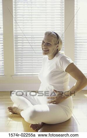 Pregnant woman sitting on the floor touching her abdomen View Large Photo Image Stock Image - Pregnant woman sitting on the floor touching her abdomen. Fotosearch