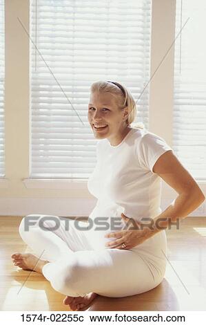 Pregnant woman sitting on the floor touching her abdomen View Large Photo Image Stock Image - Pregnant woman sitting on the floor touching her abdomen. Fotosearch