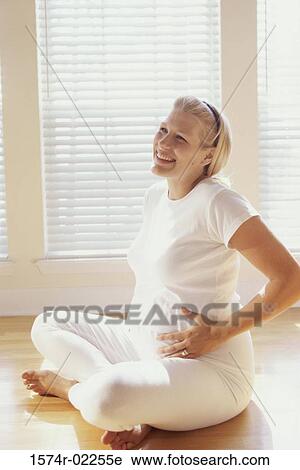 Pregnant woman sitting on the floor touching her abdomen View Large Photo Image Stock Image - Pregnant woman sitting on the floor touching her abdomen. Fotosearch
